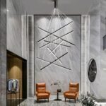 Modern black aluminium chandelier on grey background with two brown armchairs