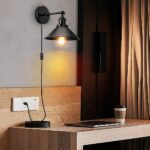 Vintage black wired wall light, displayed lit above a bedside table