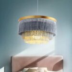 Bohemian fringed round pendant above a bed in a blue room