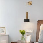 Lantern-style brass wall light in black and gold hanging next to a bed