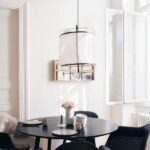 Designer white linen pendant in a dining room, above a round black table