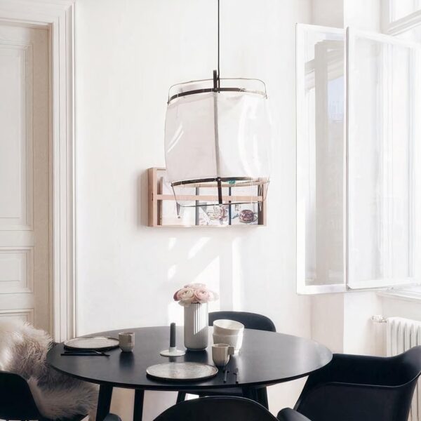 Designer white linen pendant in a dining room, above a round black table