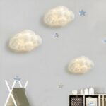 On a white wall, three white cloud-shaped sconces are lit.