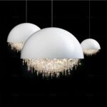 Three white globe chandeliers, half-domed at the top and showered with crystal pearls at the bottom. One in close-up facing us, one in the background on the left and one in the background on the right. On a black background.