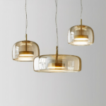 Three suspended glass fixtures, a large one in the center and two smaller ones on the sides, the one on the right is higher than the one on the left. On a gray background.