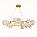 Hanging chandelier, with several glass balls of different sizes attached to a gilded metal circle, suspended by 3 wires from the ceiling light base. On a white background.