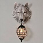 Grey wall lamp in the shape of a wolf's head, holding a black lantern on its neck
