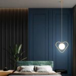Heart-shaped designer hanging lamp in a room above a bed with a blue wall