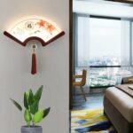 Japanese wooden LED wall light in the shape of a retro fan on a wall in a living room above a plant