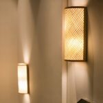 Beige bamboo lantern-style wall light in cane against the wall