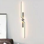 Black, geometric mirrored wall sconce. Hangs on a white wall.
