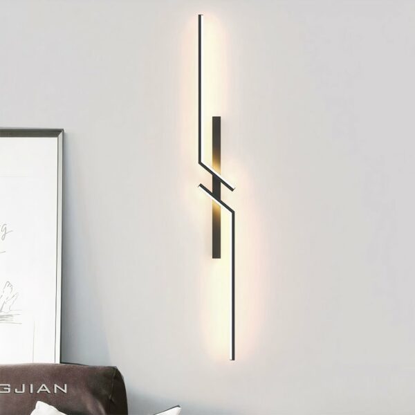 Black, geometric mirrored wall sconce. Hangs on a white wall.