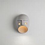 Ceramic wall lamp in the shape of a mask with yellow light inside its mouth
