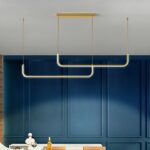Gold-coloured metal LED kitchen pendant in a kitchen with a blue wall