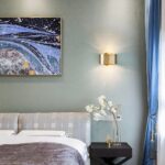 Minimalist, modern brass wall light in gold in a bedroom next to a bed