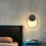Minimalist black ring LED pendant above bedside table or bed