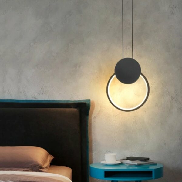 Minimalist black ring LED pendant above bedside table or bed