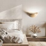 Modern ceramic wall lamp in beige next to a bed
