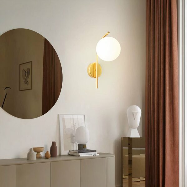 In a living room, a modern-style gold wall light hangs on the wall.