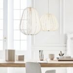 Round, tiered Japanese suspension lamp in white fabric above a simple wooden burau