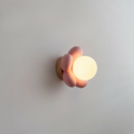On a white background, a wall sconce in the shape of a lit pink flower.
