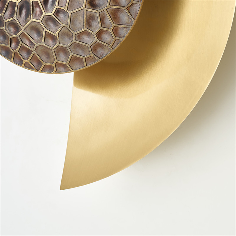 On a dark gray wall, a wall sconce hangs in the center in the shape of a lit golden half-moon.