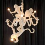 Hanging monkeys 3 animals hanging from the white chandelier, presented on a black background