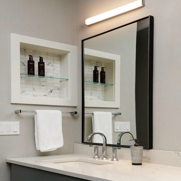 Black long unperforated bathroom wall fixture shown installed above a mirror