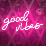 We see a pink neon wall sconce with the script good vibes lit up.