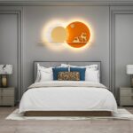Orange wall lamp with 2 deer, in 2 circles forming like 2 superimposed suns, above a bed
