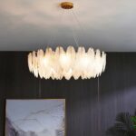 round LED leaf chandelier with white glass leaf-shaped pendants in front of a grey wall