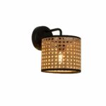 Wall lamp in rattan and black metal, featuring a round, vertical wall base with an arm angled towards the wall, housing a cylinder-shaped rattan shade. On a white background.