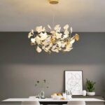 White and gold Nordic leaf chandelier in a dining room above a modern dining table
