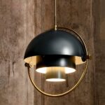 Modern art-deco globe-shaped black and gold hanging chandelier. With dark wood wall background.