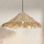 Hanging straw chandelier, conical like a hat. Woven straw, with brushed straw edges. Behind you can see a beige wall, and to the right a piece of the shade's shadow.