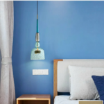 Modern LED chandelier in coloured glass on a blue background with a bed on the right