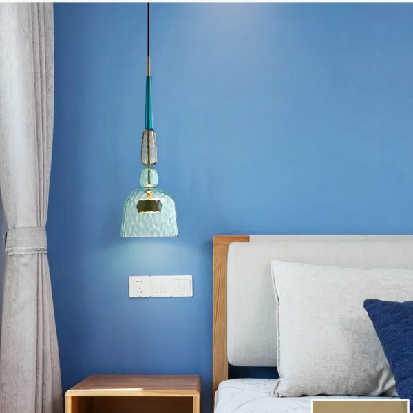 Modern LED chandelier in coloured glass on a blue background with a bed on the right