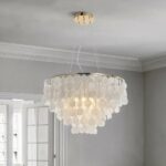 Round suspension with lots of round and flat mother-of-pearl beads cascading in a conical shape. The ceiling is light gray, and the back wall is light gray with a white-paned French window.