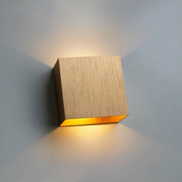 Modern square gold aluminium LED wall light on grey background