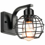 Black wall light, with square base, from which a curved arm extends, holding a cylinder with the screw thread of the bulb and the airy round shade, made of thin ring-shaped metal rods connected by other thin rods in a circular arc. With lit bulb. On a white background.
