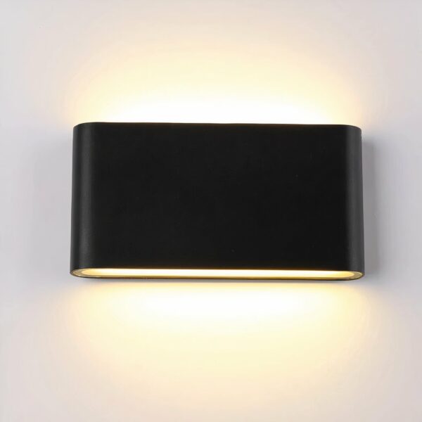 Rectangular black wall light, glued to the wall, with a light source at the top and bottom, lit. On a white wall.