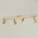 Bathroom chandelier in light wood with a large, slender rectangle as a base and 4 spaced, rotating spotlights. On a beige background.