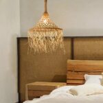 Handmade straw and rattan chandelier hanging from the ceiling and lit, in a bedroom.