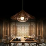 Colorful straw chandelier, exotic straw hut style, lit above a dining room table set for dinner.