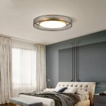 70s-style adult bedroom chandelier in fabric and gilded metal hanging from the ceiling of a bedroom and lit.
