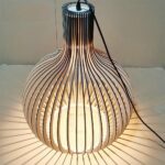 DIY solid bamboo chandelier, assembled and lit, on beige background.
