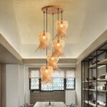 Hand-woven straw hat chandelier hanging from the ceiling and lit, above a dining room table.