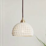 Original Scandinavian-design white pendant hanging from the ceiling and in front of a white wall.