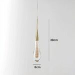 Suspension lamp in the shape of a water droplet with cable and golden head. The drop is transparent with gold glitter inside.