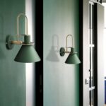 we see a green wall and two dark green Scandinavian-style wall sconces on top